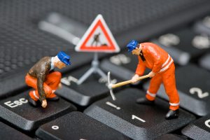 Miniature construction workers on a keyboard repairing a computer